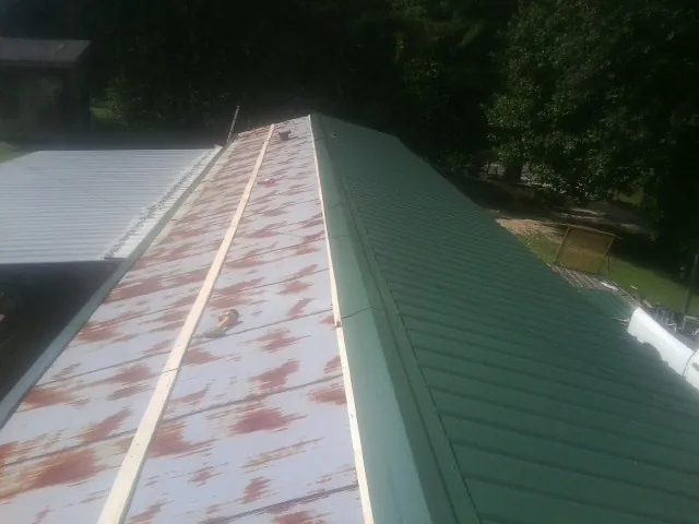 Old rusted panels beside newly installed green metal roofing — Wind Damage Roof Repair by Roofing Brothers in Sugar Land