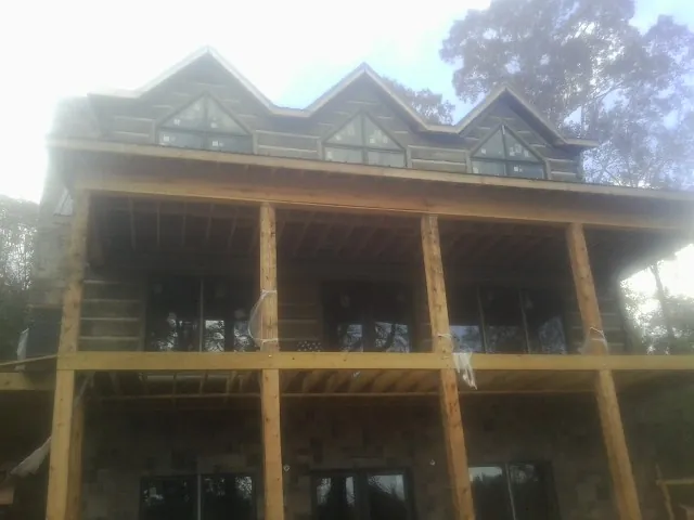 Dormers and porch framing on a large log home under construction — Roof Coating work by our crew in Sugar Land
