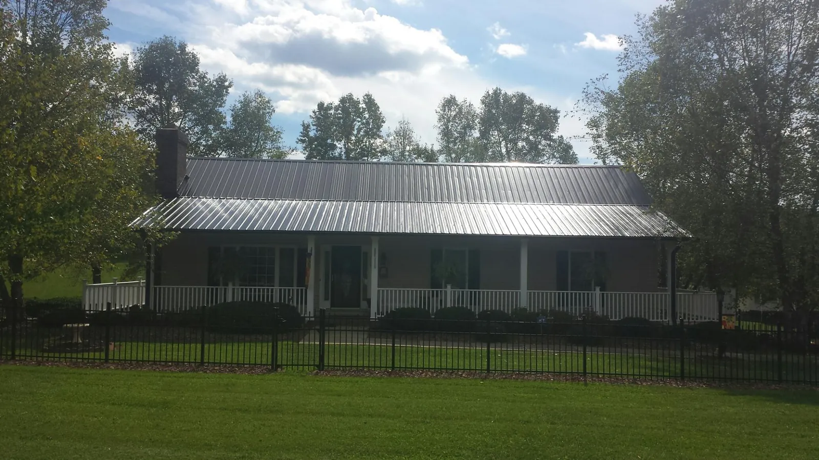Gray metal roof on a brick ranch with a full width front porch — Gutter Guard Installation work by our crew in Sugar Land