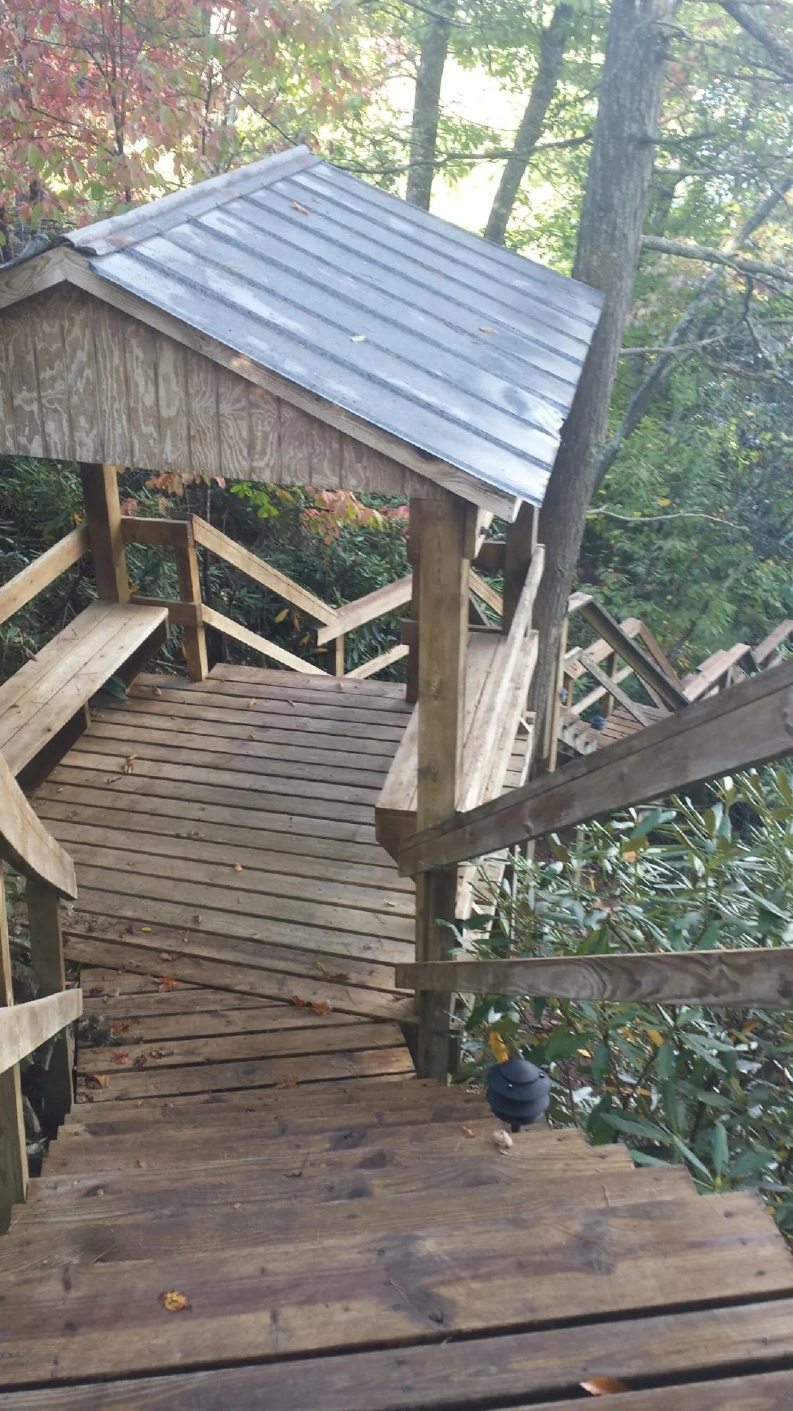 Metal roofed shelter over wooden steps on a wooded walkway — Skylight Repair & Installation work by our crew in Sugar Land