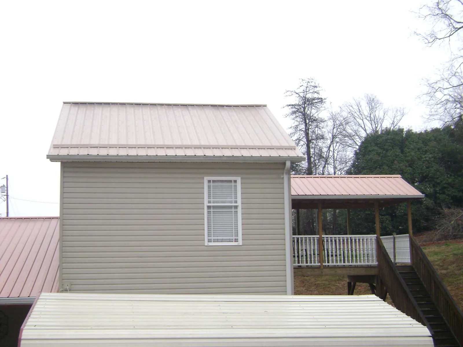 Tan metal roofs on a two story addition and attached porch, from a Roof Replacement job in Sugar Land
